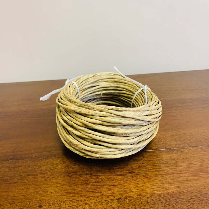 Pre Twisted Natural Rush 1 lb coil from HH Perkins on wooden table in the HH Perkins' classroom.