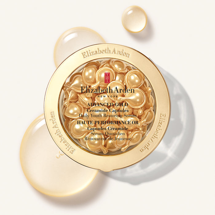 Elizabeth Arden Advanced Gold Ceramide Capsules in a round gold jar, shown open with golden capsules visible inside and additional translucent capsules floating around it on a light background.