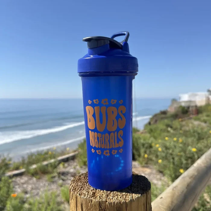 BUBS Naturals Blue Blender Bottle on a coastal overlook