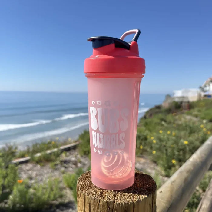 BUBS Naturals Coral Blender Bottle on a coastal overlook