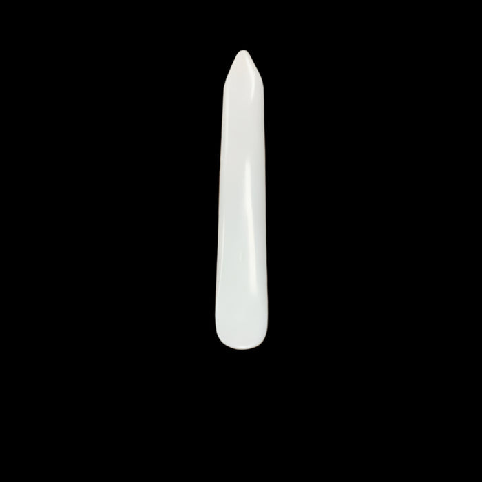 A bone awl with a tapered and rounded edge, placed on a wooden surface.