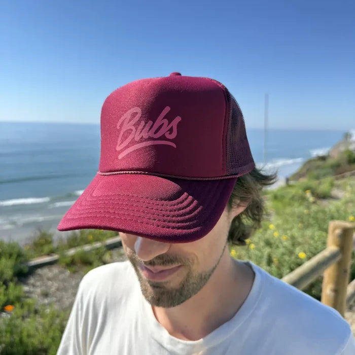 Person wearing a BUBS Burgundy Trucker Hat outdoors