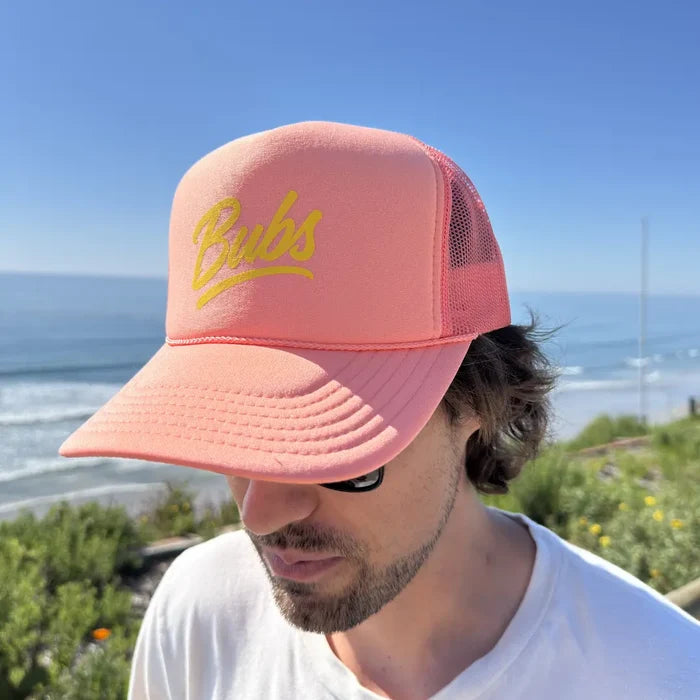 Person wearing a BUBS Coral Trucker Hat outdoors