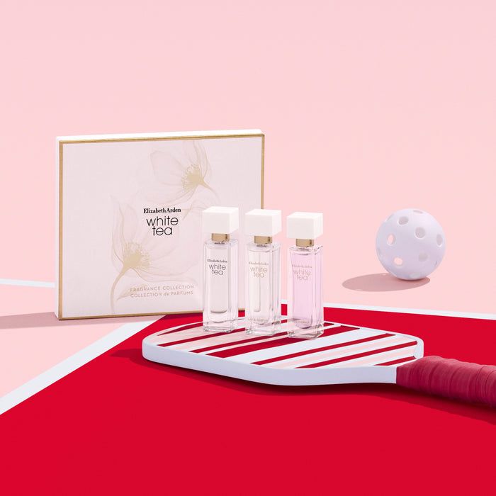 Three perfume bottles on a red and white striped stand with a box labeled 'White Tea' on a pink background.