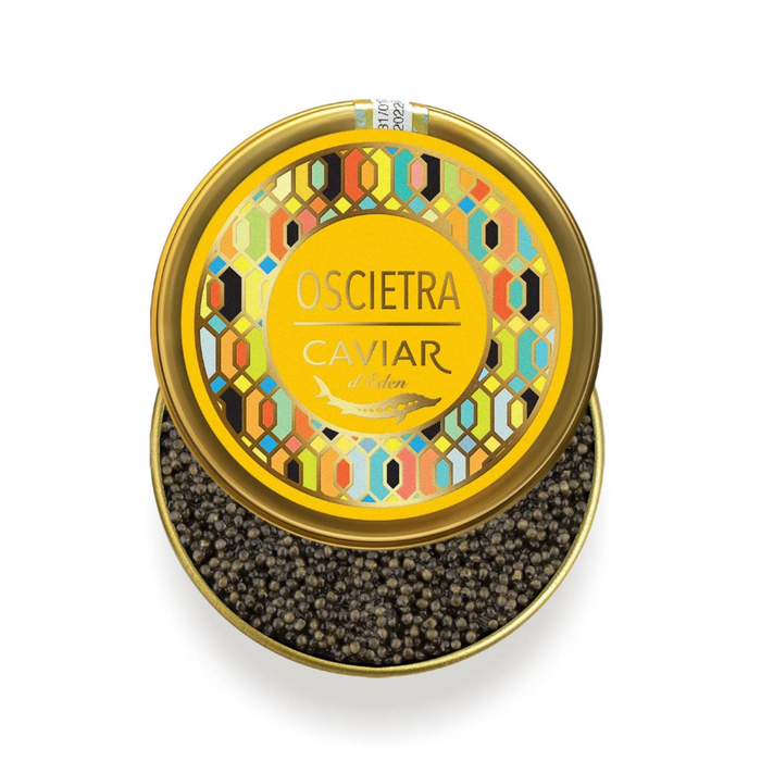 Top-down view of an open golden tin of Caviar d'Eden Oscietra, revealing rich, dark premium sturgeon caviar pearls and a vibrant geometric lid