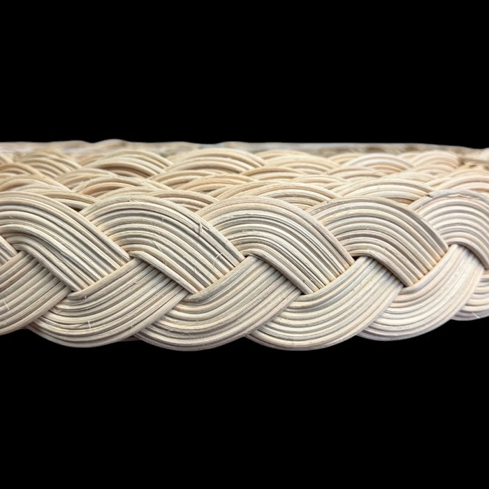 A close-up of a braided reeds made of light natural rattan, shown against a solid black background