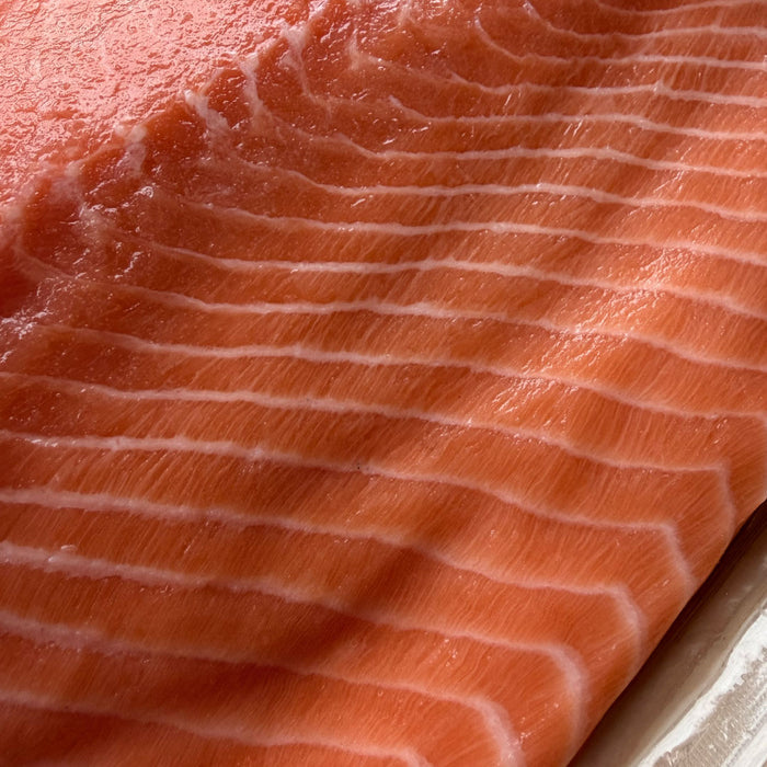 Iš arti matoma SASHIMI kokybės atlantinės lašišos filė be odos – ryški spalva, tekstūra ir natūralios baltos riebalų linijos