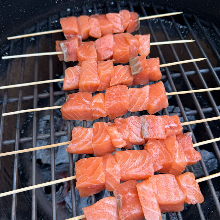 SASHIMI kokybės atlantinės lašišos filė be odos gabalėliai, suverti ant medinių iešmelių ir paruošti kepimui virš žarijų grilyje