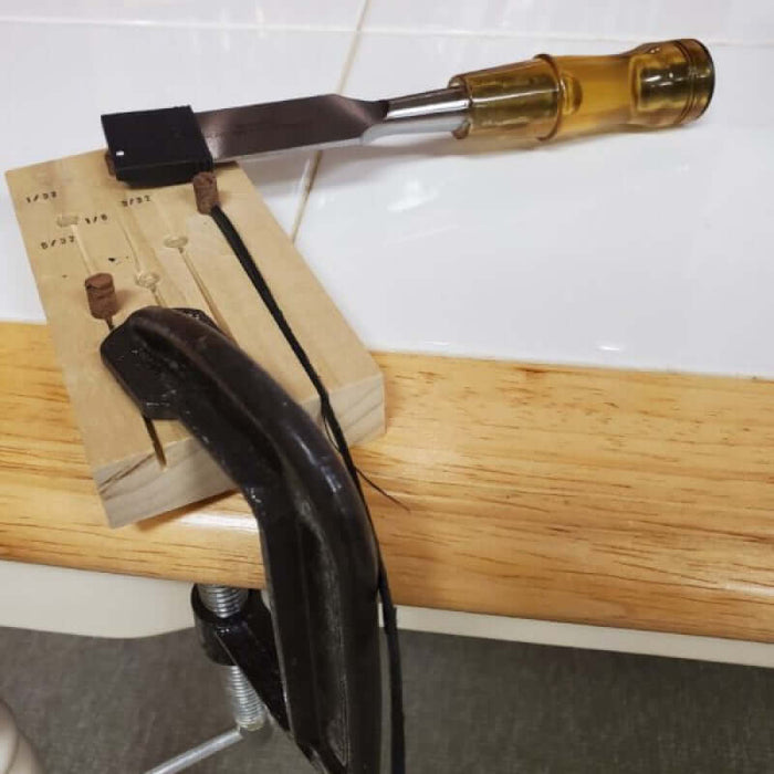 Stave Shaver fastened to the table with c-clamp. A strand of black cane rests in the stave shaver's groove waiting to be shaved with the 1" Chisel.