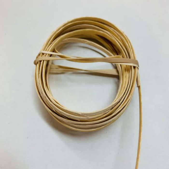 A bundle of light brown cane strands, approximately 5mm thick, tied together on a white background.